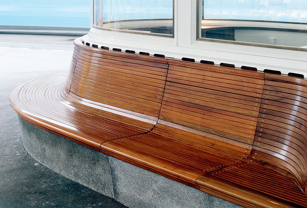 Curved wooden bench with backrest at a public bus stop